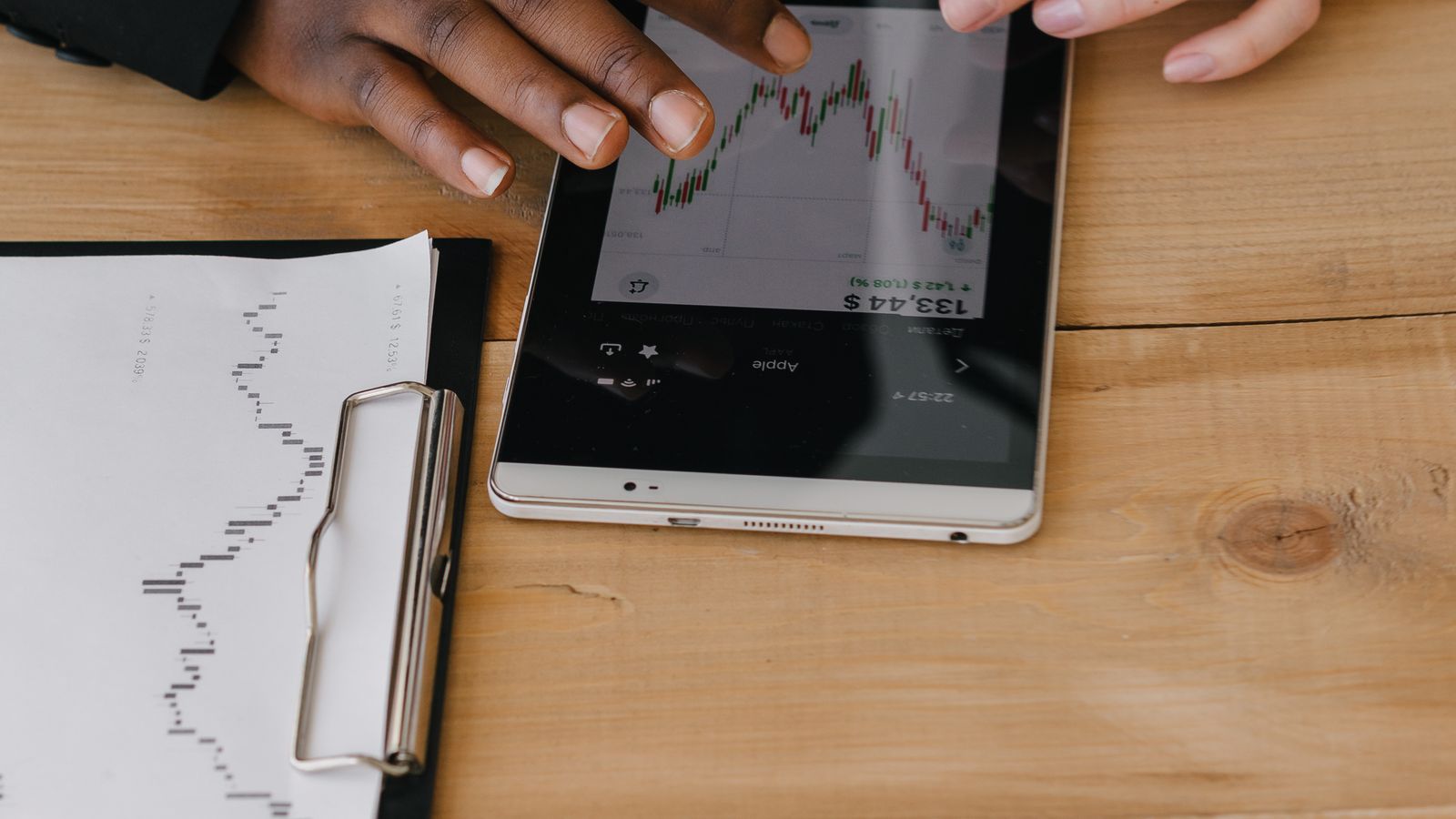 オフィスでタブレットの金融チャートを確認するビジネスパーソン2人のイメージ。AI投資拡大に伴う社債発行ラッシュと長期金利への影響を連想させる。