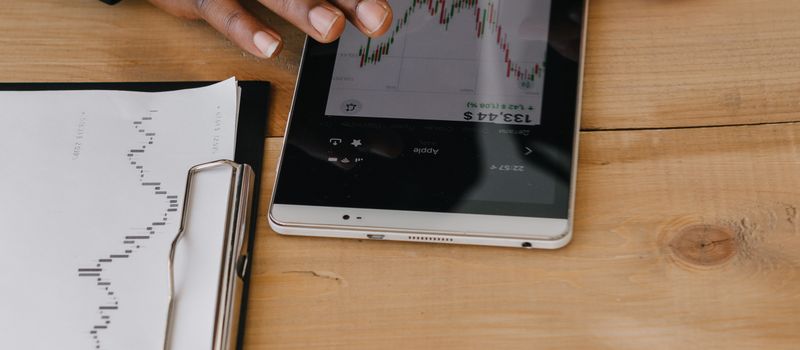 オフィスでタブレットの金融チャートを確認するビジネスパーソン2人のイメージ。AI投資拡大に伴う社債発行ラッシュと長期金利への影響を連想させる。