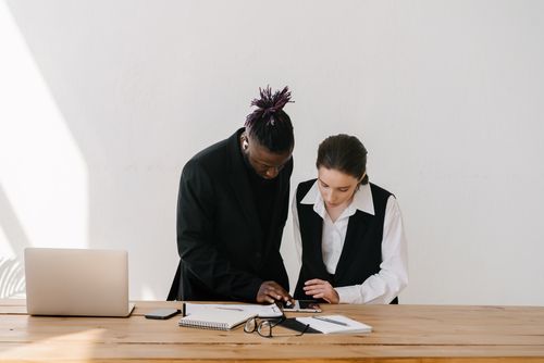 Free Two colleagues working together at a wooden table in an office setting. Stock Photo