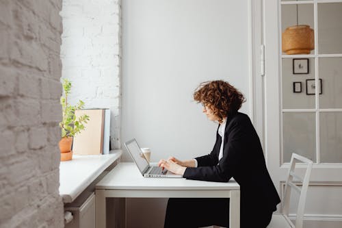 Woman in Black Long Blazer Using a Laptop