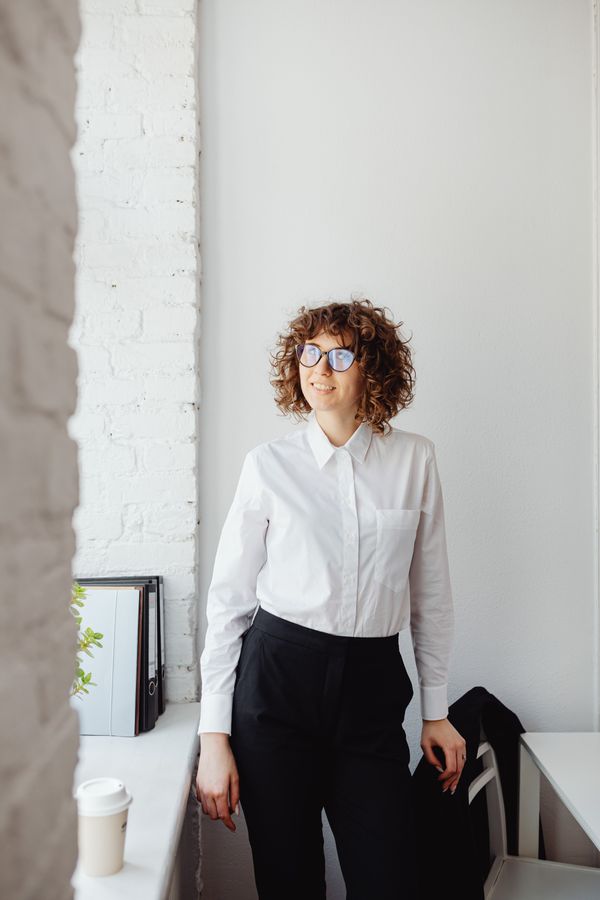 Woman wearing a relaxed white shirt tucked into tailored trousers