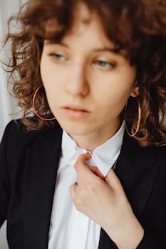 Close-up portrait of a professional woman in a black suit adjusting her white collar shirt.