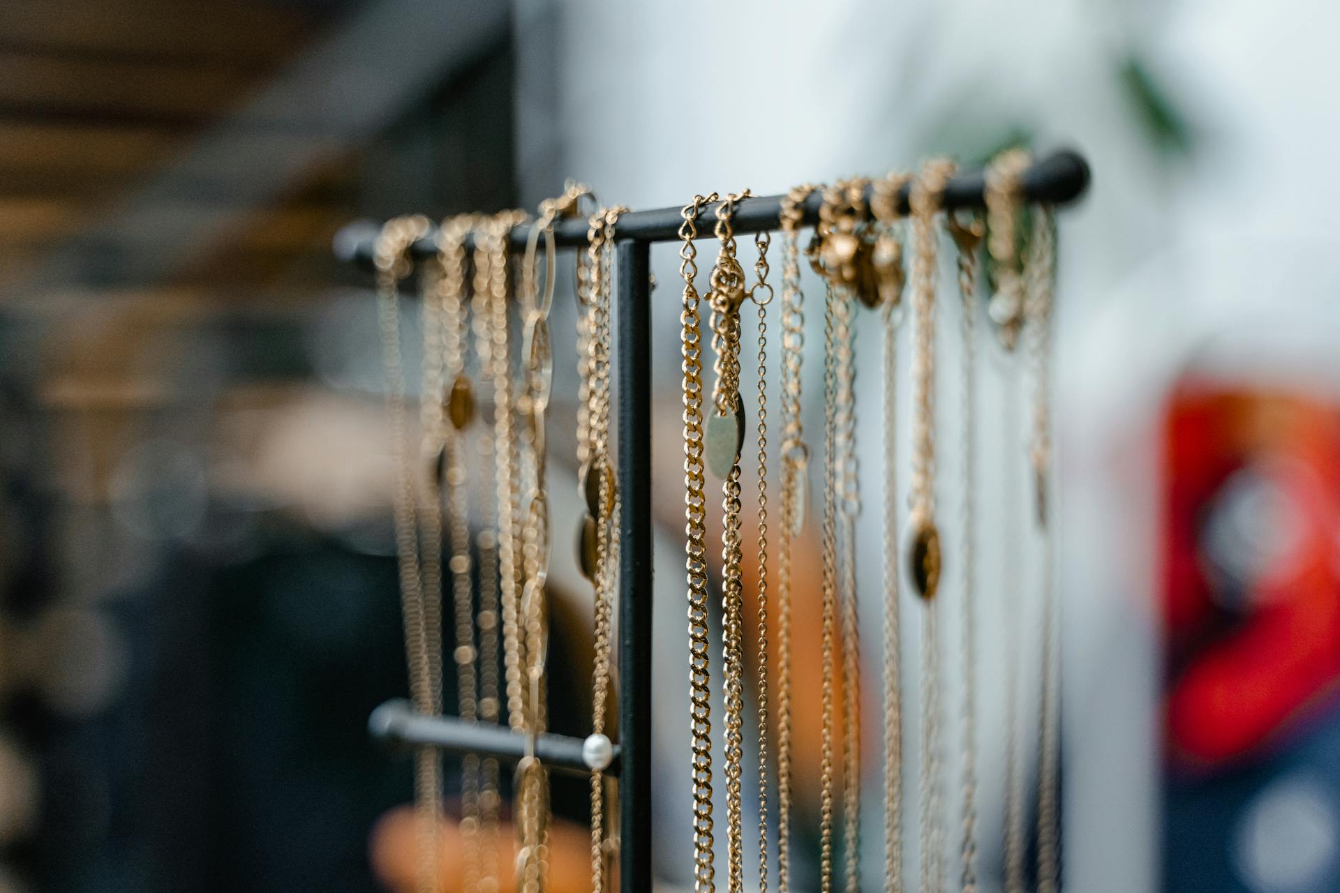 Close-up of gold necklaces displayed on a jewelry stand for elegant interior decor.