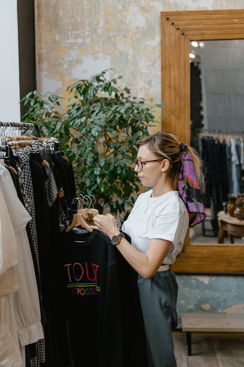 Woman in White Shirt Near the Clothing Rack