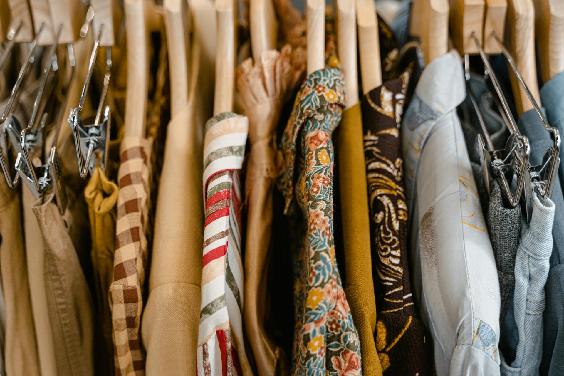 A variety of colorful clothes neatly hung on wooden hangers in a store setting.