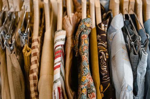 Free A variety of colorful clothes neatly hung on wooden hangers in a store setting. Stock Photo