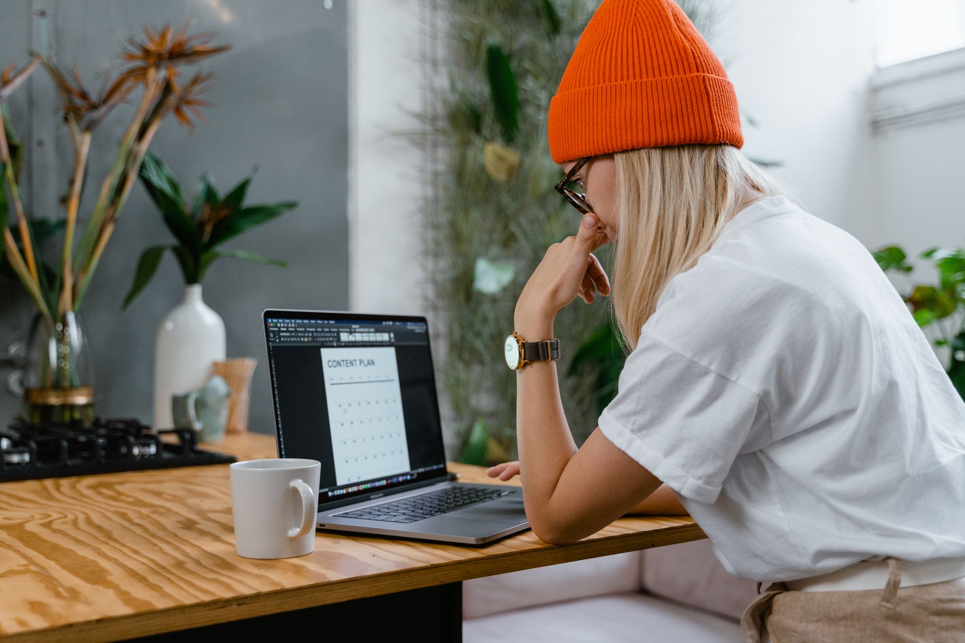 A Person in Orange Knit Cap Using Laptop