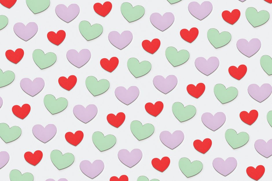 A delightful pattern of colorful paper heart cutouts in red, green, and purple on a light background.