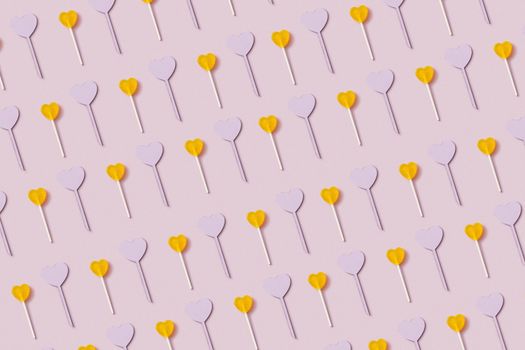 A vibrant pattern of heart-shaped lollipops on a pastel pink background, perfect for festive and romantic themes.