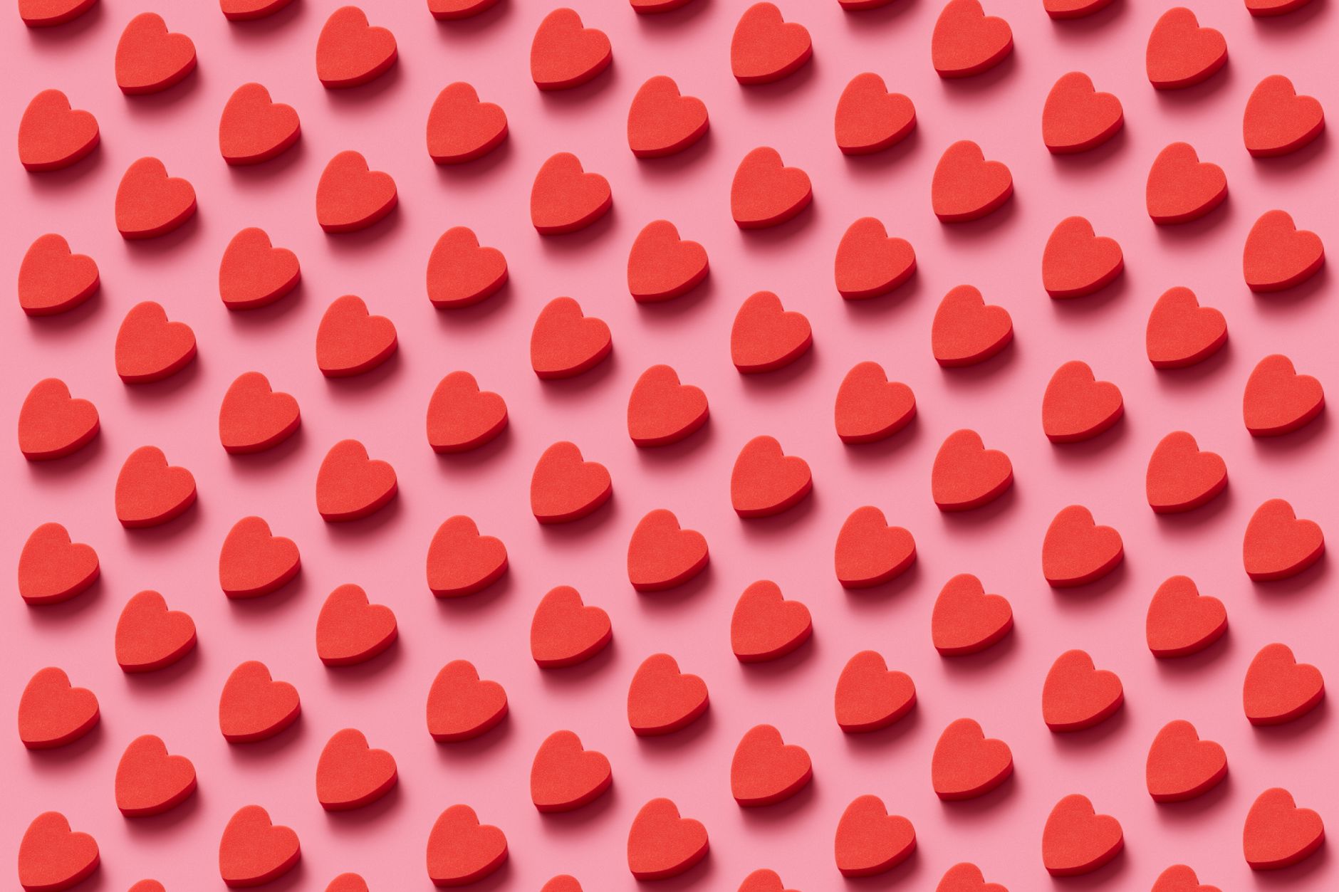 long covid heart palpitations relief — Vibrant red heart candies arranged in an eye-catching diagonal pattern on pink.