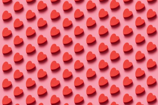 Vibrant red heart candies arranged in an eye-catching diagonal pattern on pink.