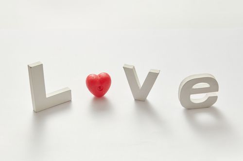 Free White letters spelling LOVE with a red heart on a white background, minimal design. Stock Photo