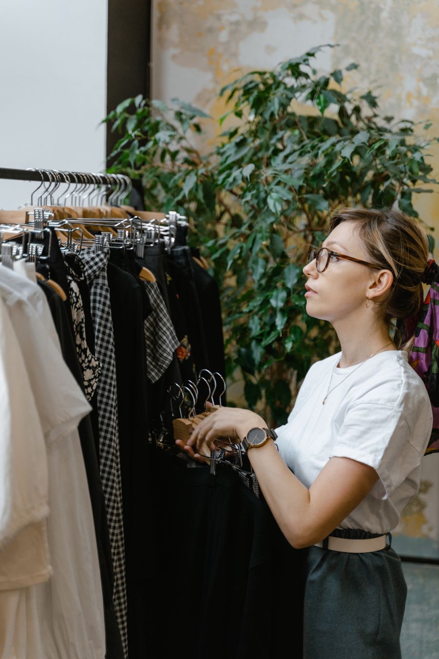 A woman choosing pieces from a rack of dresses in a fitting room.