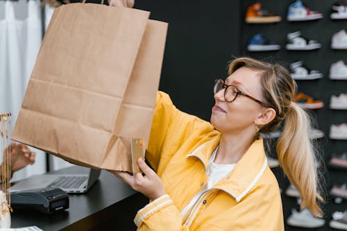 Woman in Yellow Jacket Holding Brown Paper Bag