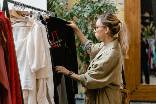 Free Fashion enthusiast browsing clothing rack in boutique store, selecting attire. Stock Photo