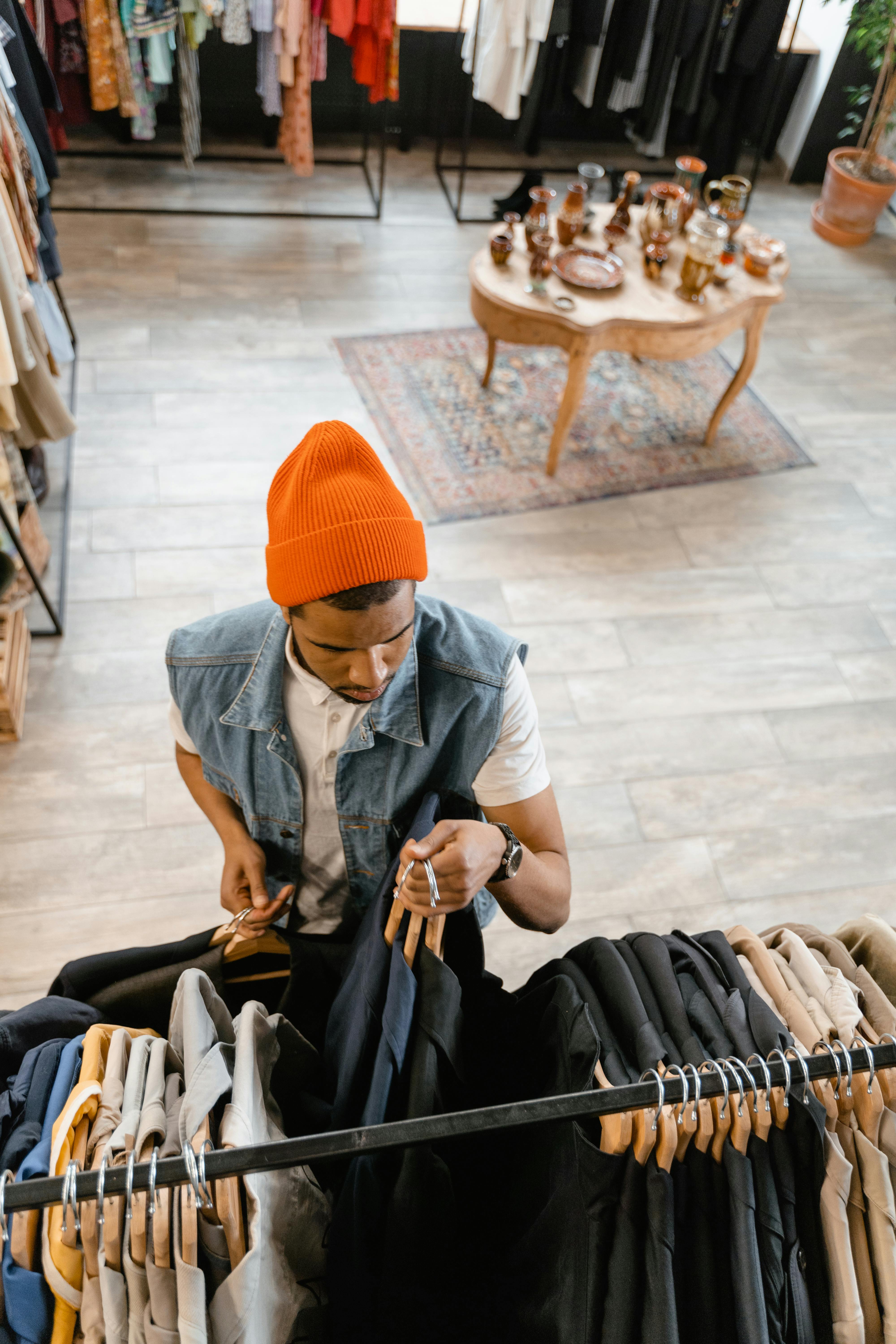 man in orange knit cap putting clothes on the clothes rock