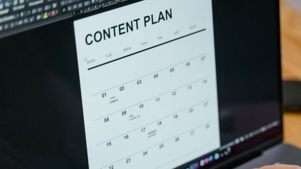 Close-up of hands typing on a laptop displaying a content plan document
