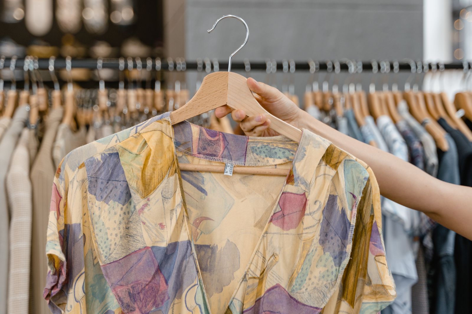 Hand holding a printed vintage blouse on a hanger