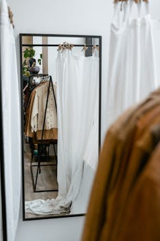 Modern clothing boutique with fitting room mirror and hanging garments.