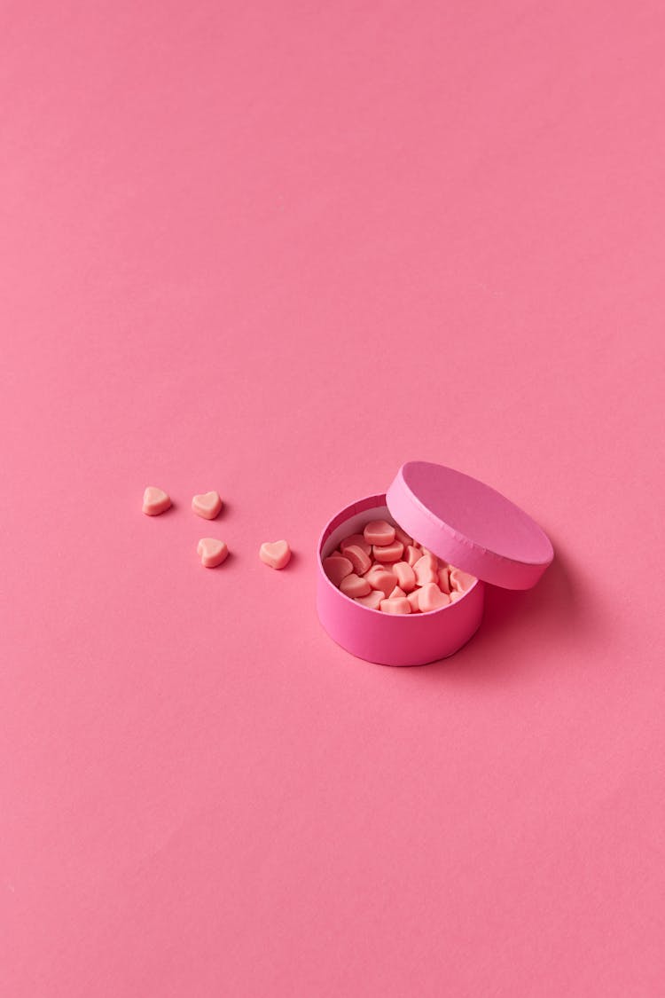 Heart Shaped Pills On Pink Background 