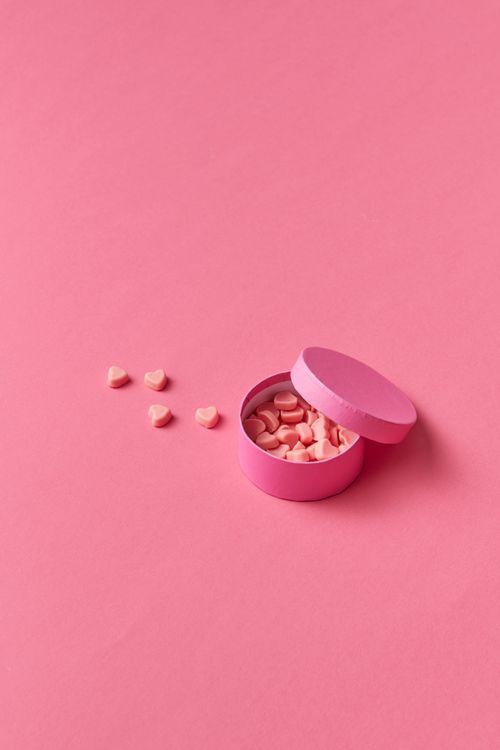Free Minimalist photo of heart-shaped candies in an open pink box on a pink background. Stock Photo