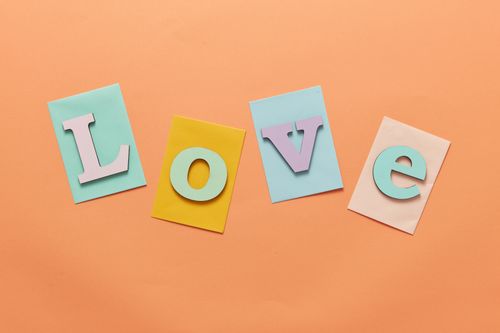 Free Vibrant letters spelling 'Love' on colorful paper against an orange background. Stock Photo