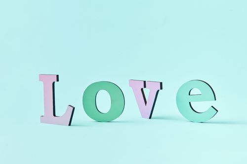 Free Pastel colored wooden letters spelling 'Love' on a teal background, offering serene vibes. Stock Photo