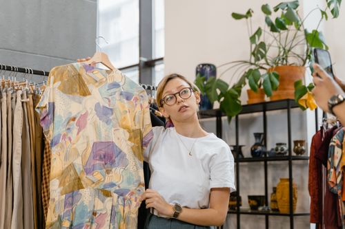 Free A woman showcasing a colorful dress in a stylish boutique setting, ideal for online selling. Stock Photo