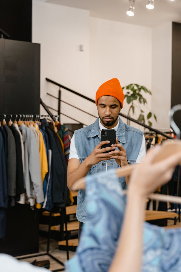 A Man Wearing Orange Beanie Holding Black Smartphone