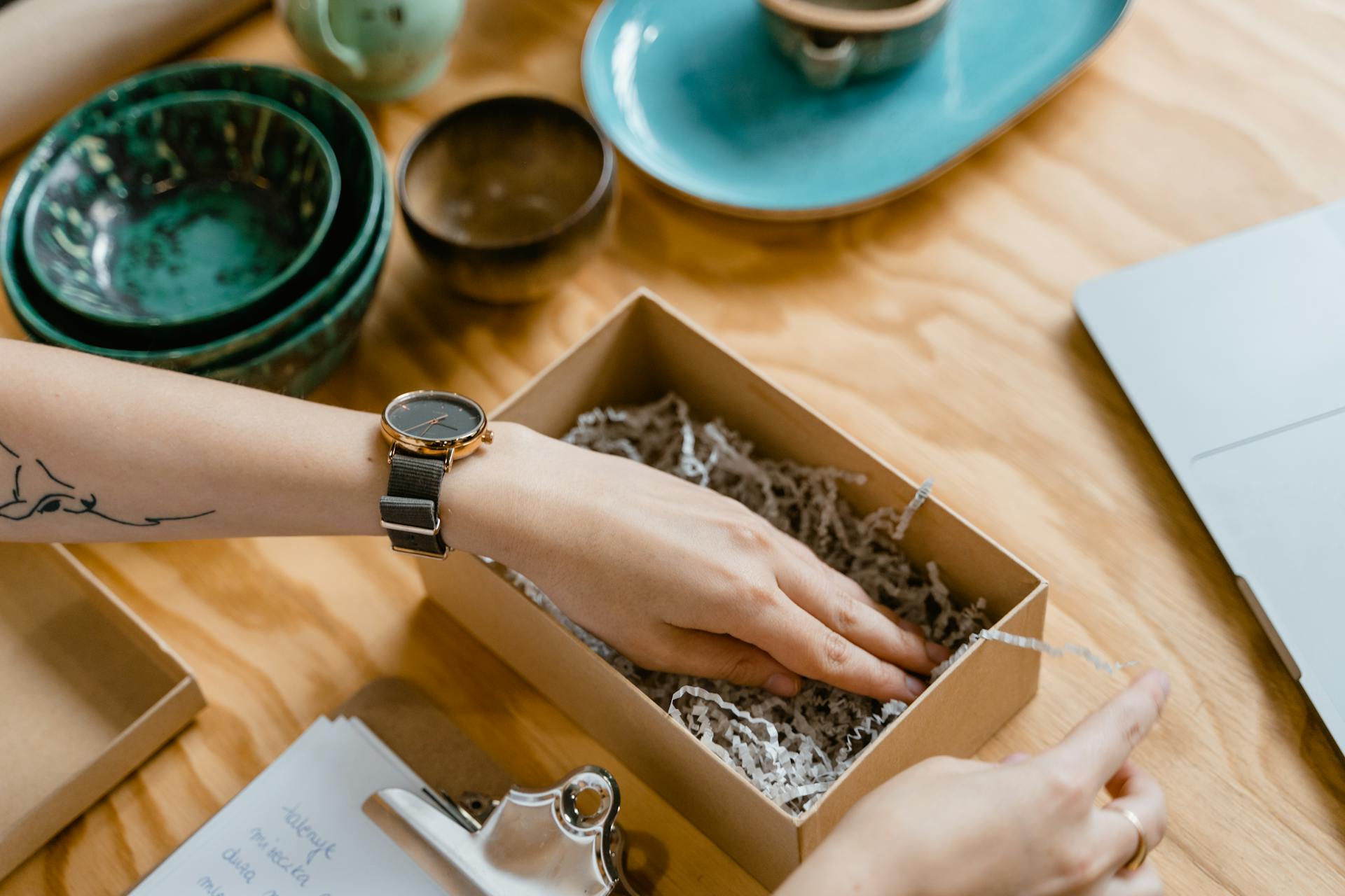 Person Putting Shredded Paper in a Brown Cardboard Box