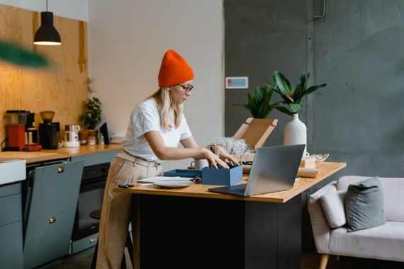 Customer using a laptop while unpacking an online order in a modern kitchen