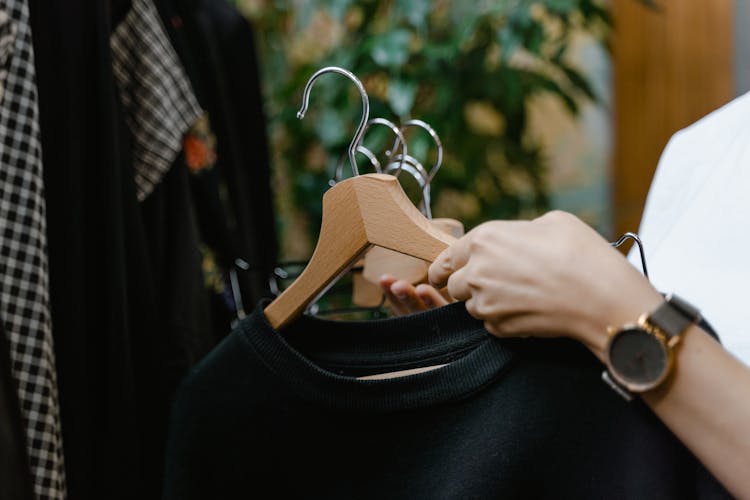 Person Holding Clothes On Hangers