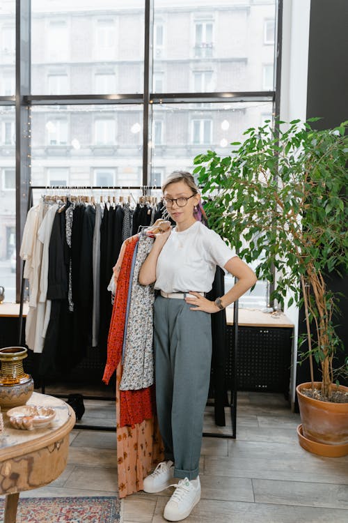 Woman in White Shirt Holding Clothes on Hanger