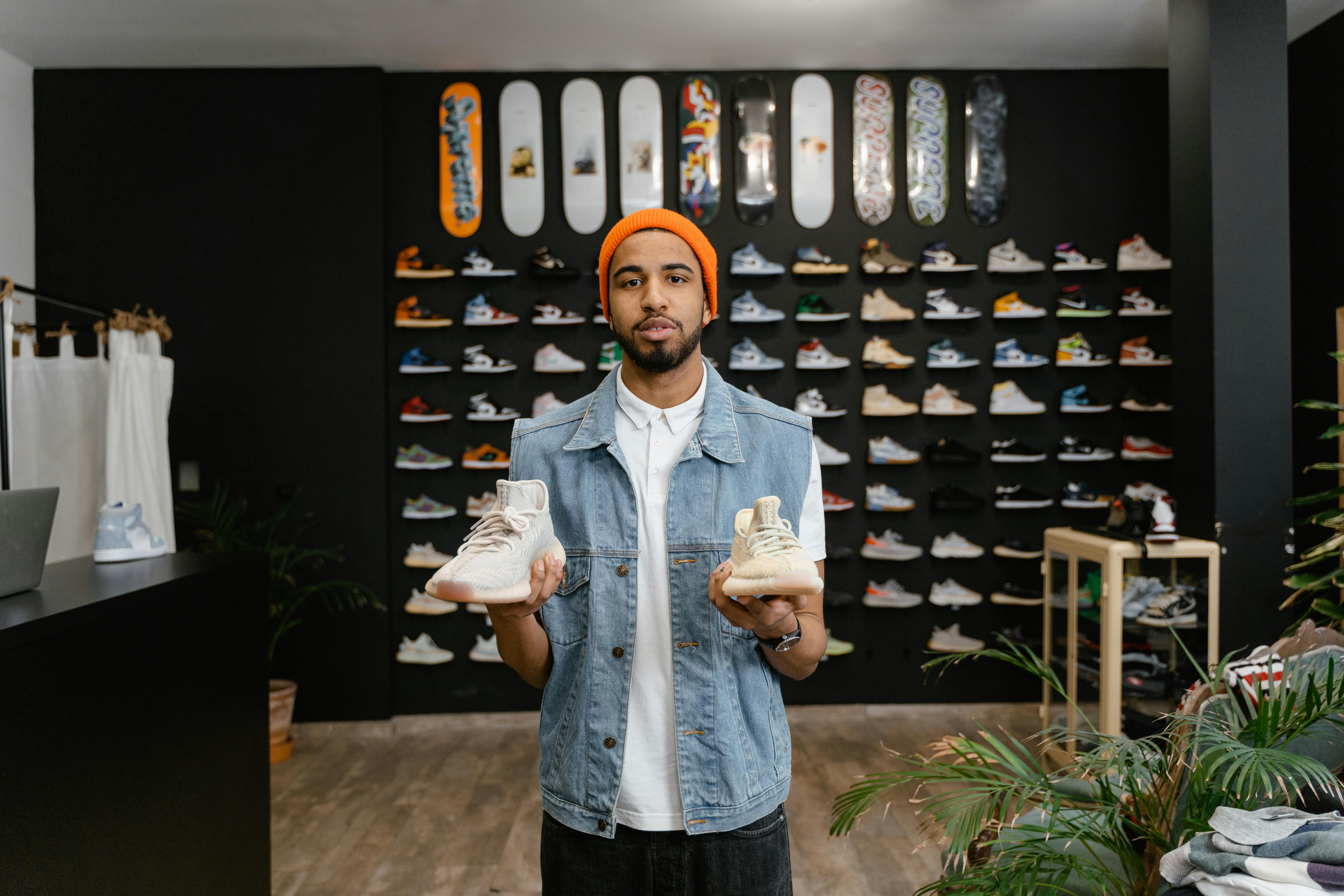 bearded man in denim vest holding a pair of white shoes