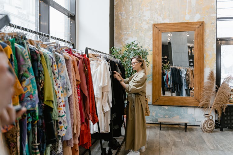 Woman In Brown Trench Trench Coat Standing Near Clothes Rack