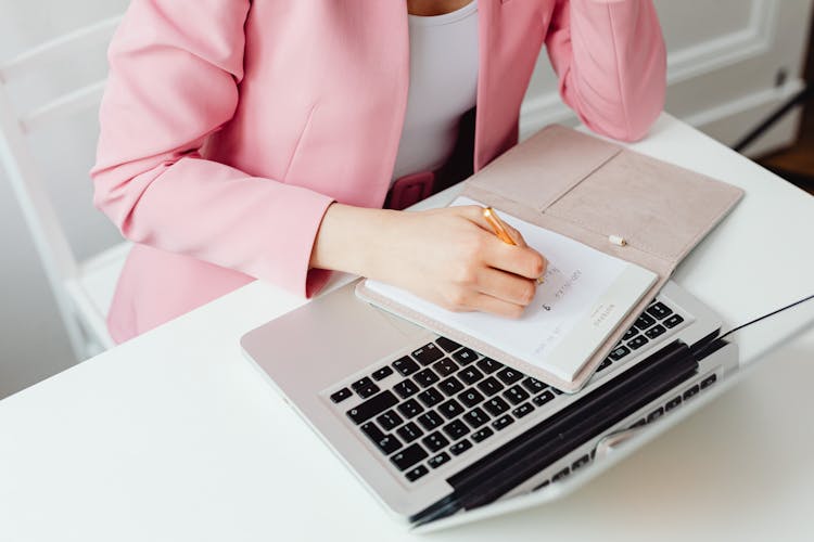 Woman In Pink Blazer Writing On Notepad