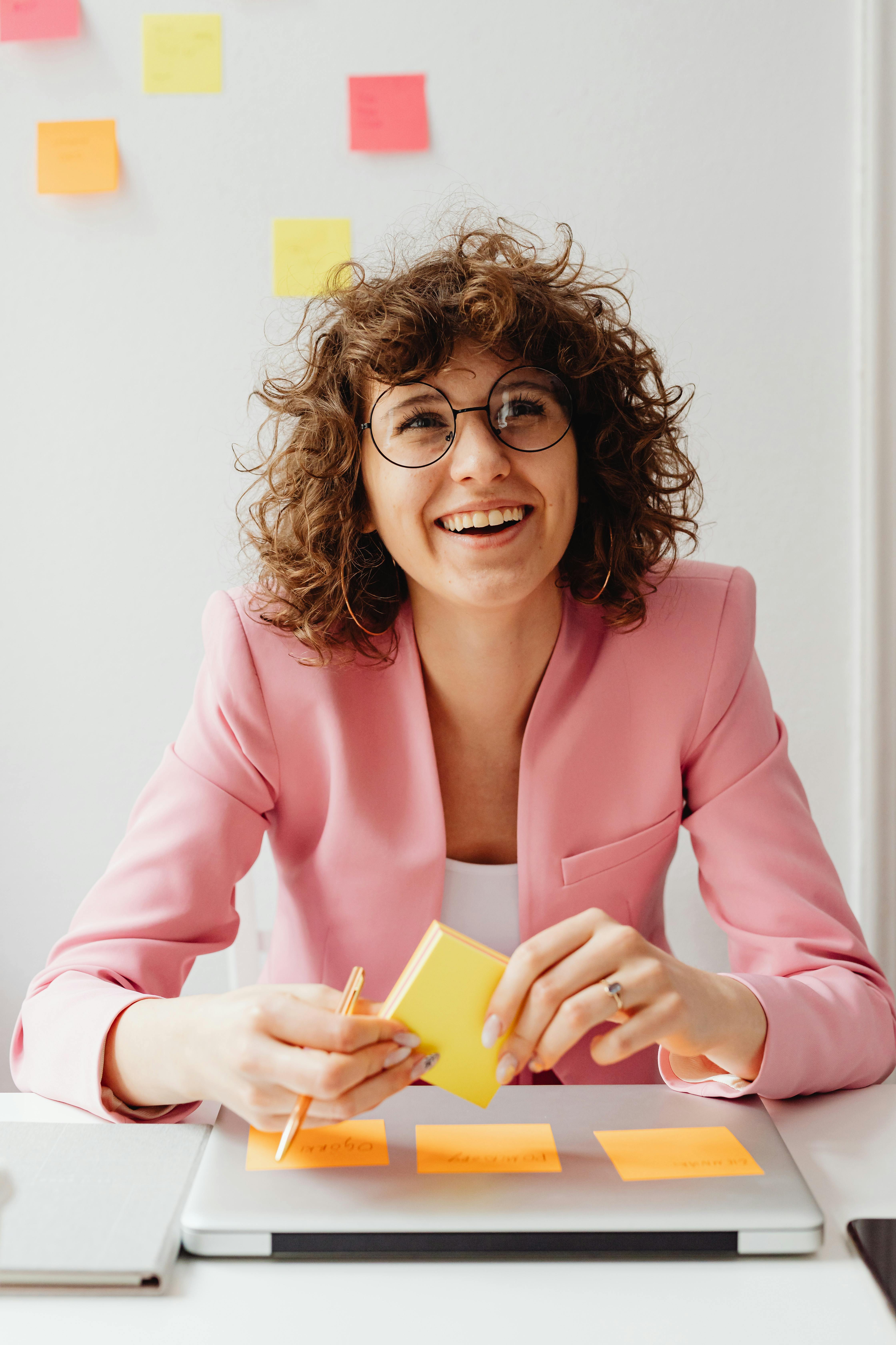 woman in pink blazer holding sticky notes