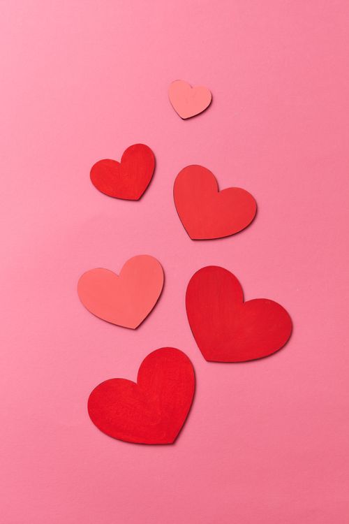Free Red and pink heart cutouts on a pink background, perfect for romantic themes. Stock Photo