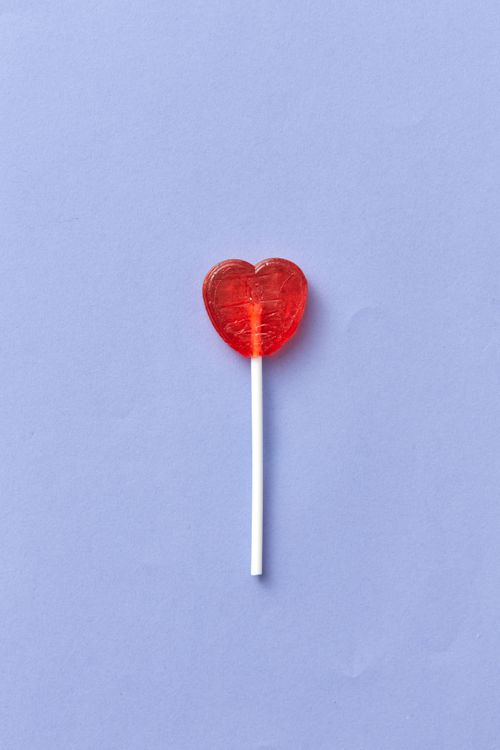 Free Red heart lollipop on blue backdrop, perfect for Valentine's themes. Copy space available. Stock Photo