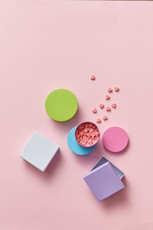 Free Flat lay of colorful boxes and heart confetti on a pink background, creating an artistic abstract composition. Stock Photo