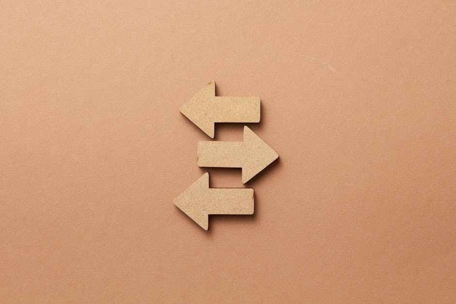 Close-up of three wooden arrows pointing in opposite directions on a beige surface.
