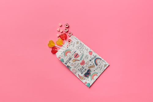 Heart Shaped Candies and Lollipops on Pink Background 