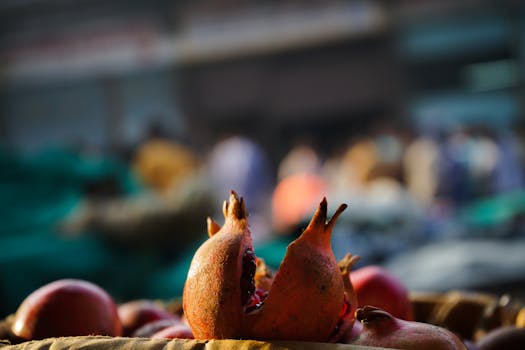 Close-up of fresh pomegranates at a bustling outdoor market, showcasing their vibrant color and organic texture.