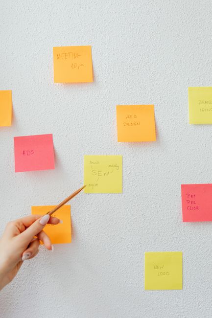 A hand pointing to vibrant sticky notes arranged on a white wall, highlighting planning and organization. - How to Create a Monthly Blog Content Calendar That Keeps You Consistent