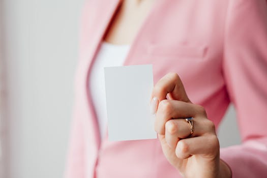 Close-up of a woman's hand holding a blank business card with a blurred background for design mockup.