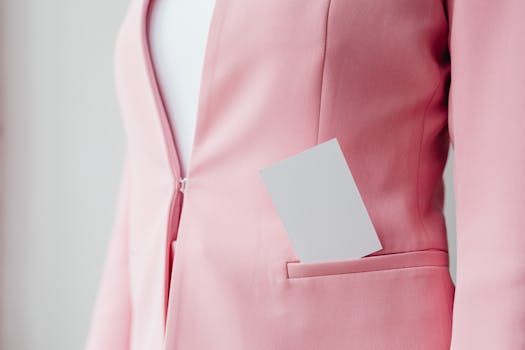 Close-up of a pink blazer featuring a business card in the pocket, stylish and professional.
