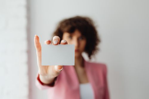 Free A professional woman in pink suit presenting a blank business card indoors. Stock Photo