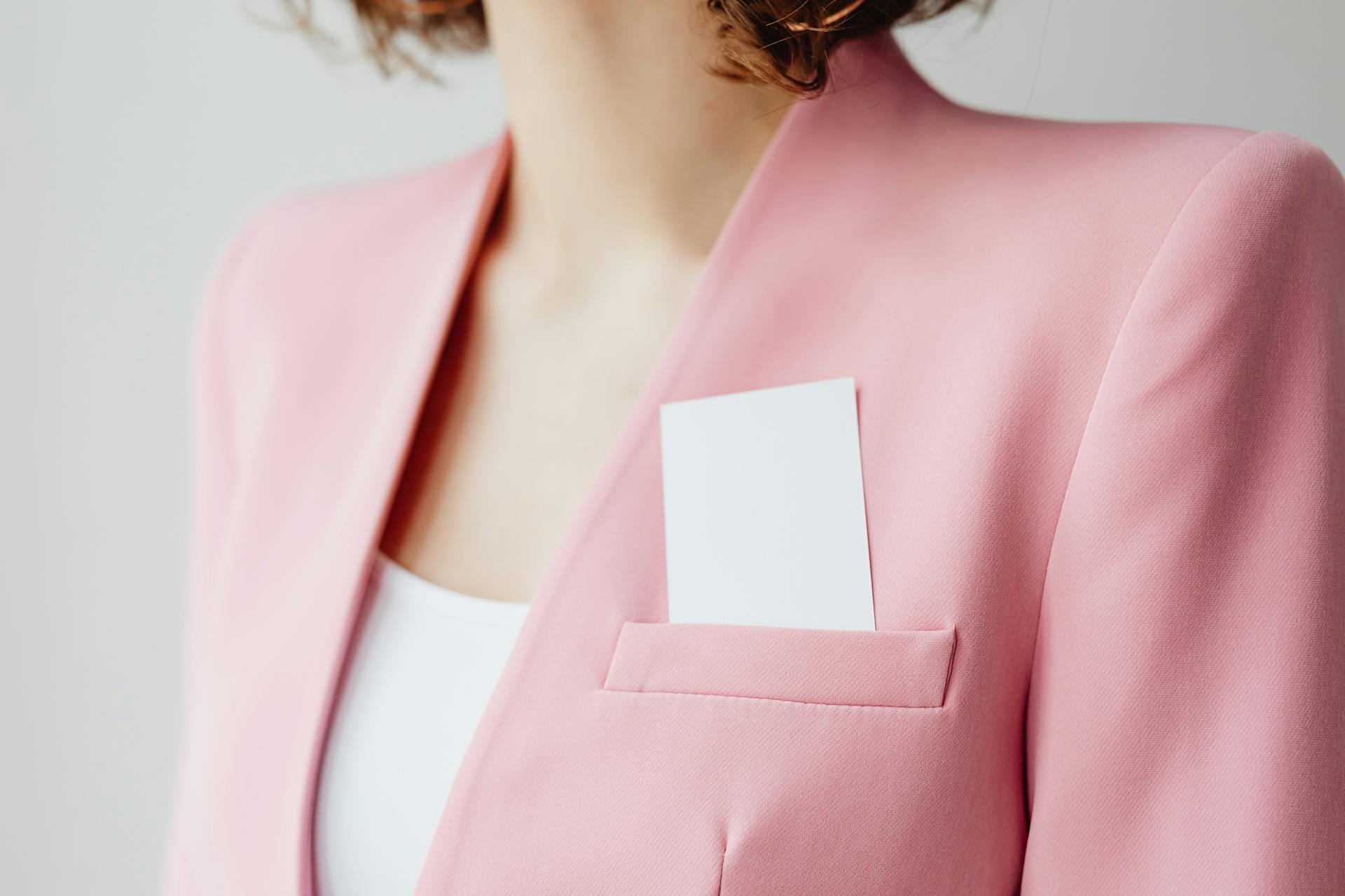 Person in Pink Blazer with White Card in Pocket