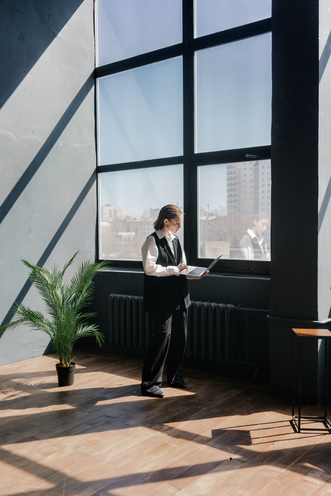 Professional reviewing a laptop beside an office window