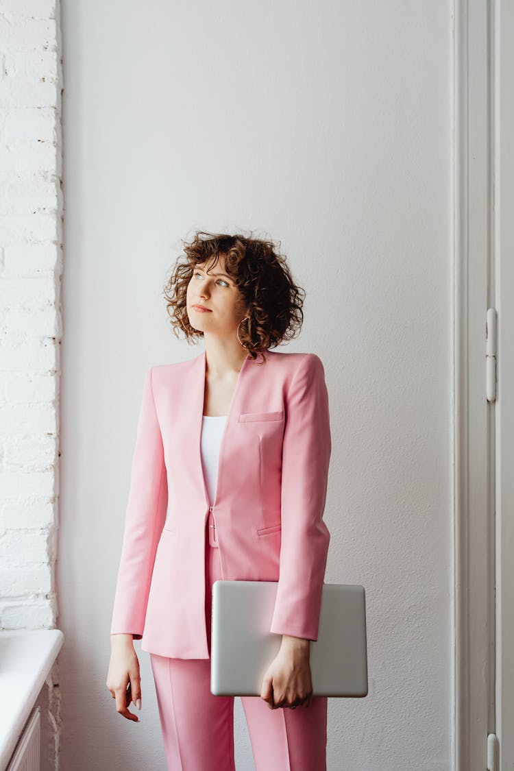 Woman In Pink Suit Carrying A Laptop